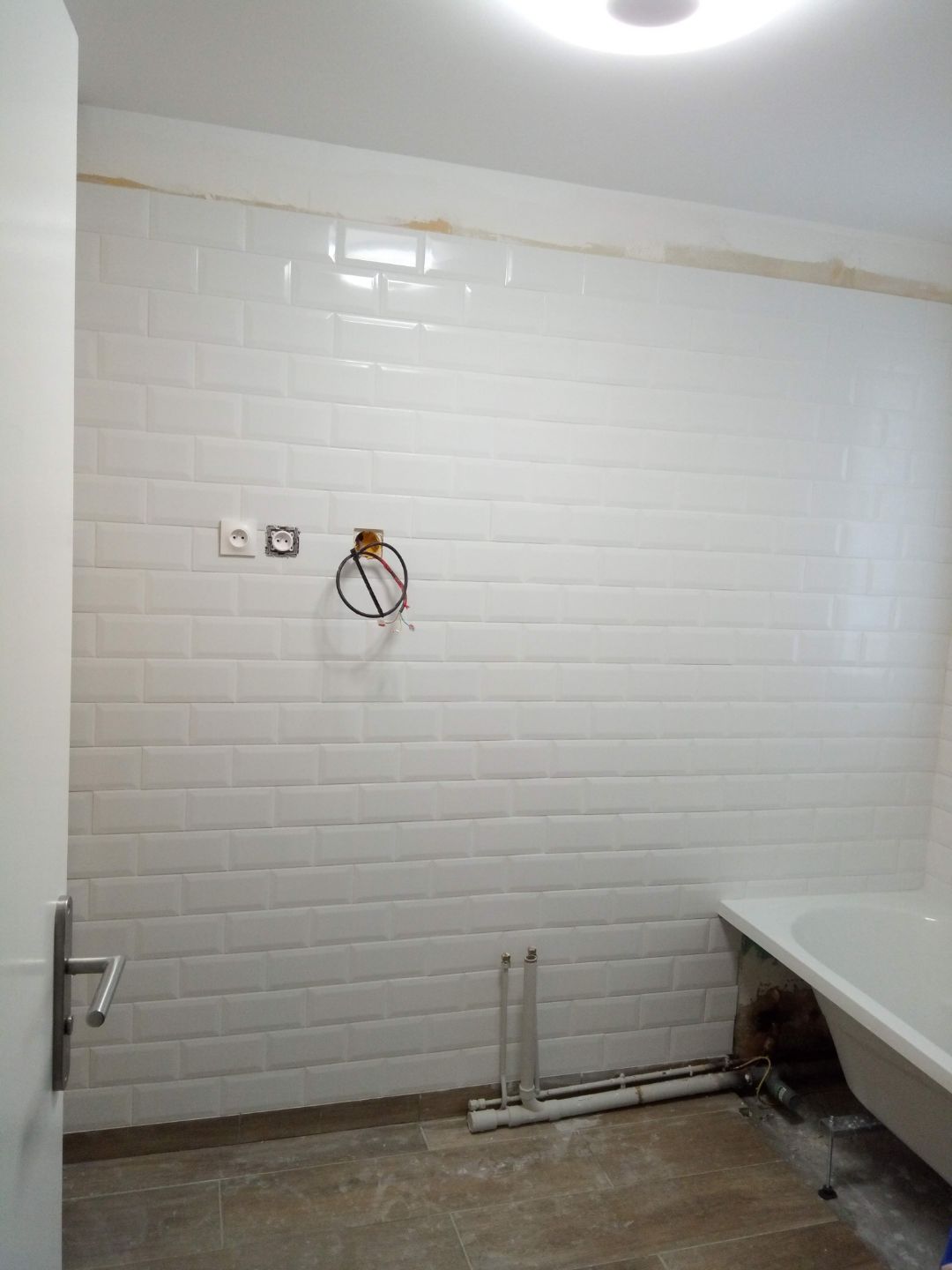 Pose de faïence murale type briques blanches dans une salle de bain